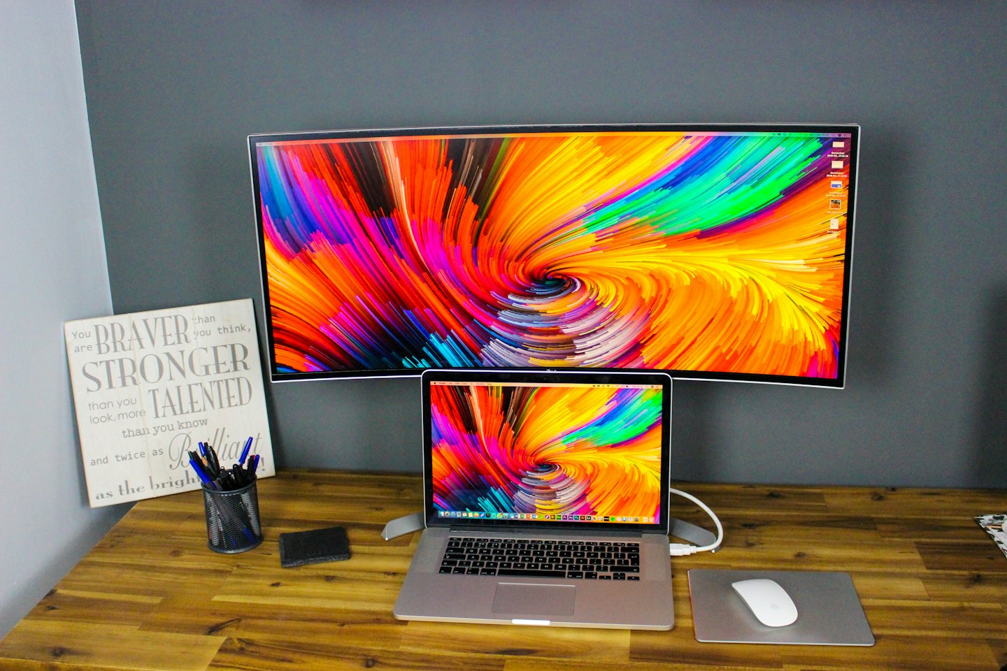 Workstation featuring a curved monitor and laptop on a wooden desk.