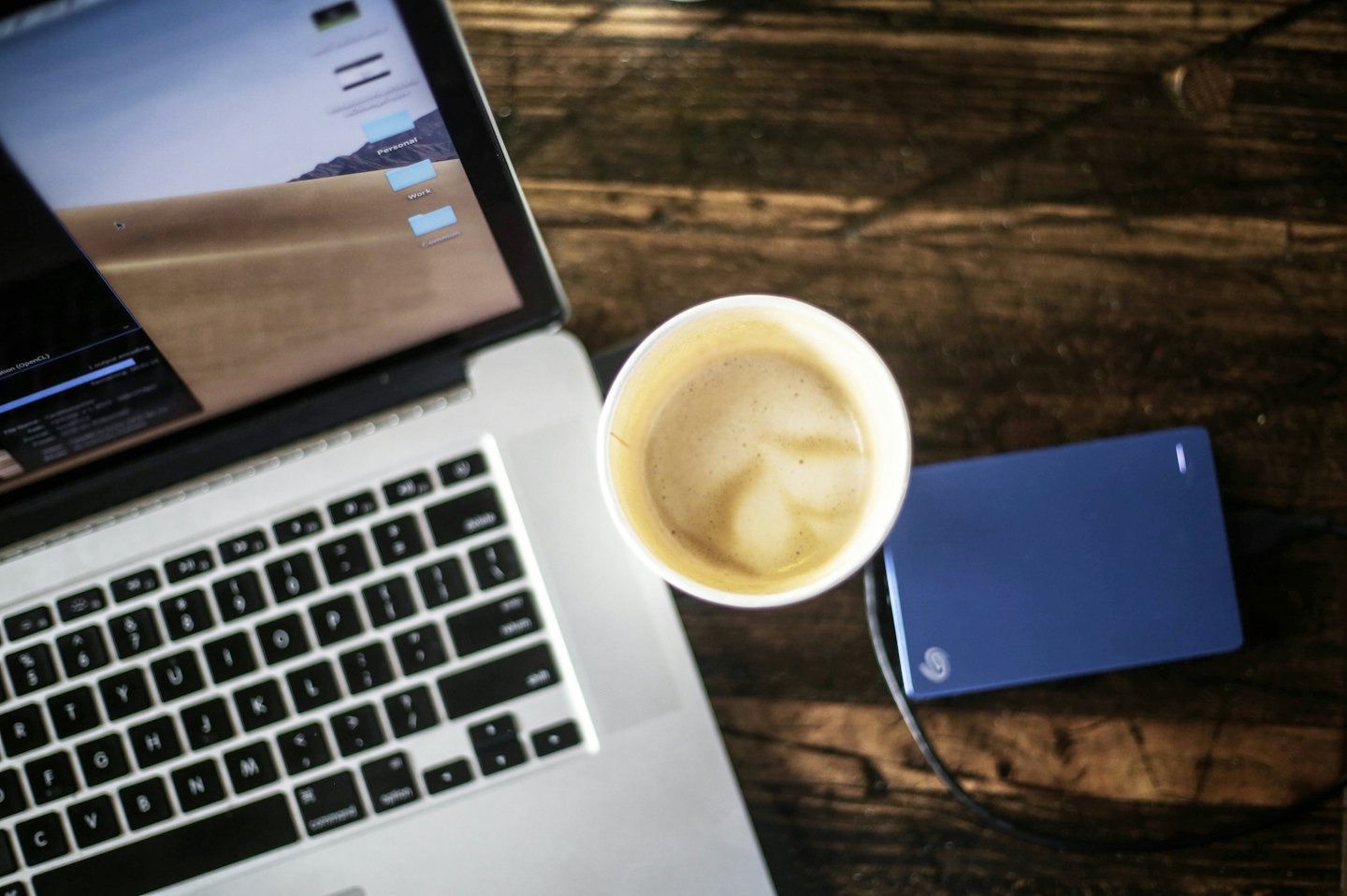 Laptop with work folders and latte art on desk.